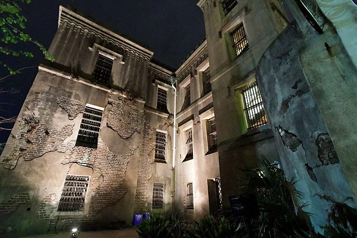 Illuminated corner of the Old Charleston Jail building with brickwork at night.